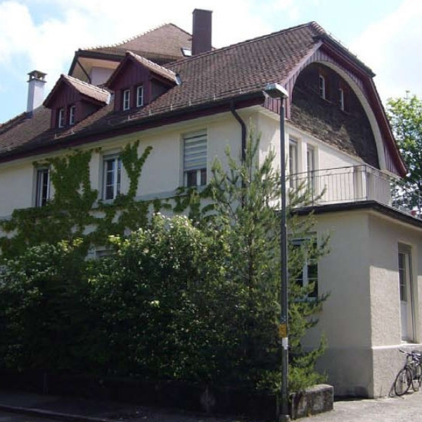 BSI Software Standort in Bern – Aussenansicht eines traditionellen Wohnhauses mit Satteldach und Fensterläden, umgeben von Bäumen und Efeu.