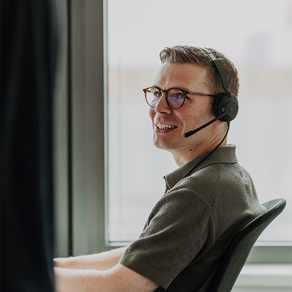 Lächelnder Mitarbeiter mit Headset im Kundengespräch im modernen Büro der BSI in Düsseldorf – professionelle Kundenbetreuung und IT-Services.
