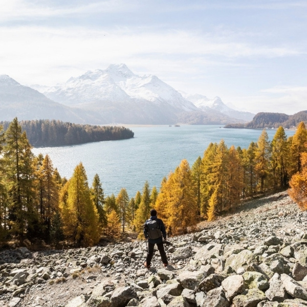Urs Frick von BSI Software beim Wandern in herbstlicher Berglandschaft mit Blick auf den Silsersee im Engadin, eine Kamera in der Hand haltend.