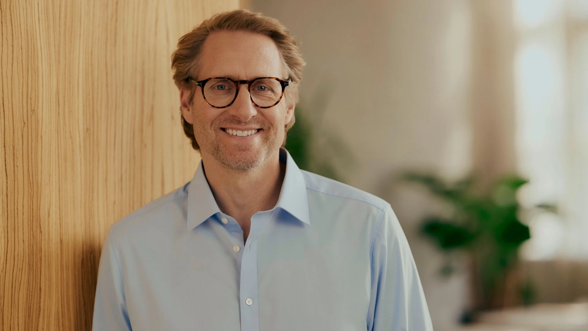 Portrait d’un décideur souriant d’une entreprise d’approvisionnement en énergie dans un environnement professionnel moderne. Il symbolise la digitalisation des fournisseurs d’énergie et montre comment un CRM moderne pour les fournisseurs d’énergie soutient la Customer Experience, des processus efficaces et des relations clients durables.