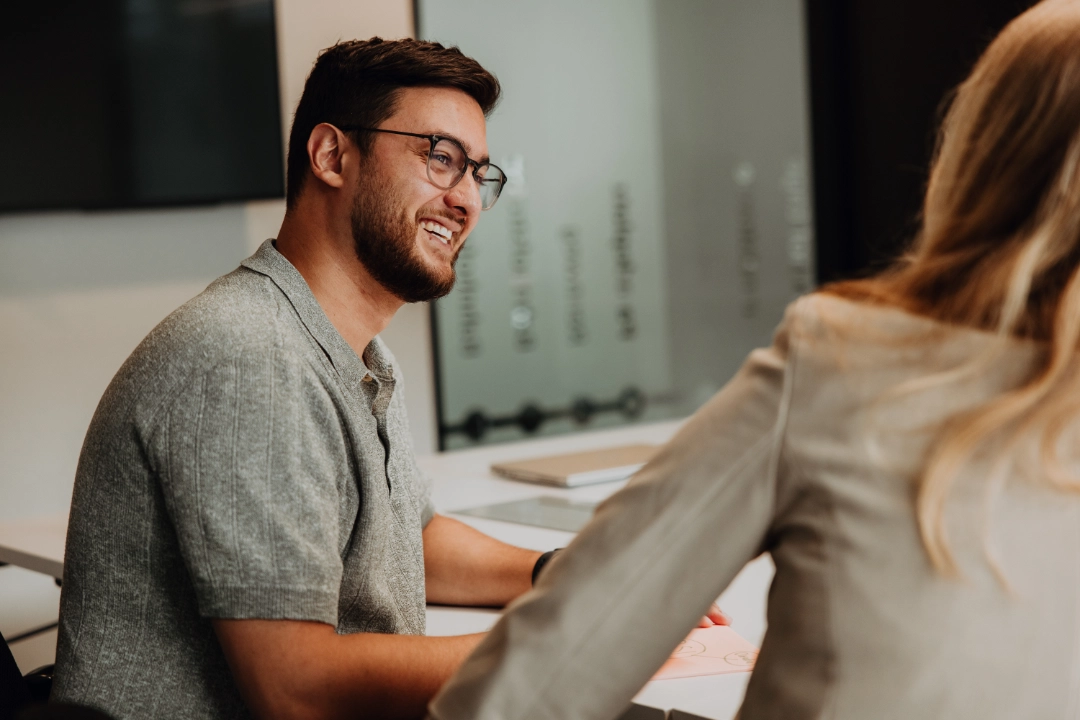 Deux collaborateurs discutent à table, sourient et échangent des idées – communication ouverte, développement personnel et environnement favorable pour réussir son entrée dans la vie professionnelle chez BSI Software.