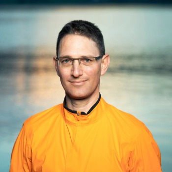 Porträt von Thomas Lindauer, Software Engineer bei BSI Software, im orangen Sportoberteil vor ruhigem Wasser im Abendlicht.
