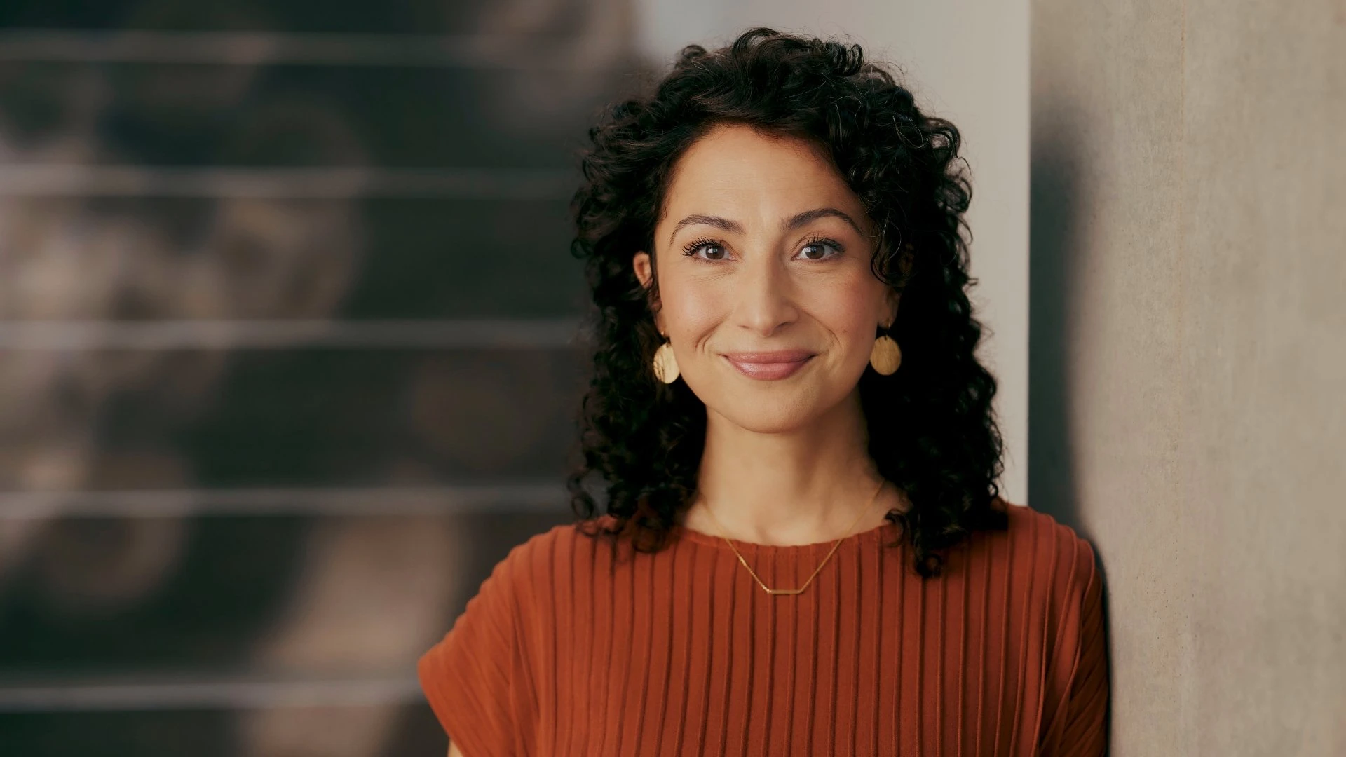 Portrait d’une femme souriante dans un environnement professionnel moderne. Elle symbolise une décideuse du secteur de l’assurance qui fait avancer la digitalisation dans les assurances grâce à un CRM moderne pour les assurances.