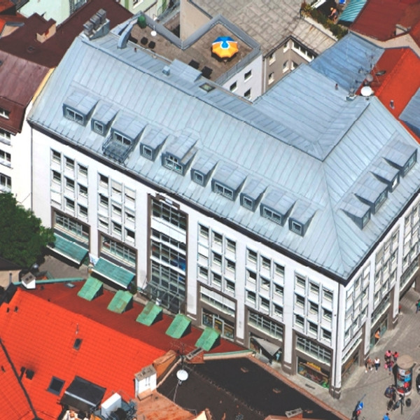 BSI Software Standort in München – modernes Bürogebäude mit markanter Dachkonstruktion in zentraler Innenstadtlage und sichtbarem BSI Sonnenschirm auf der Dachterrasse.