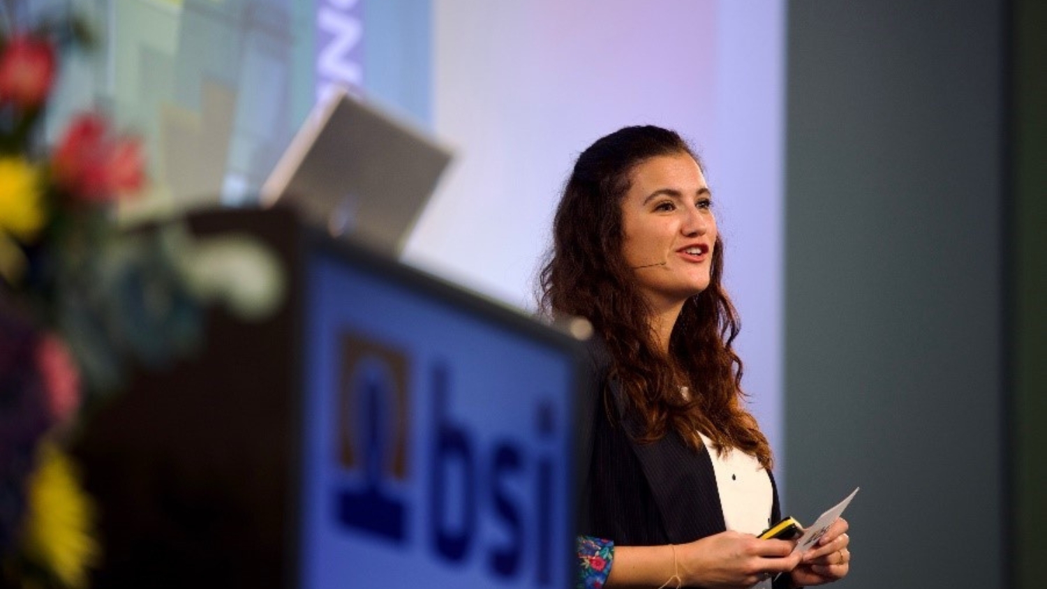 Verena Kuhr von BSI Software beim Vortrag am BSI Customer Summit 2024 – auf der Bühne mit Headset und Notizen in der Hand.