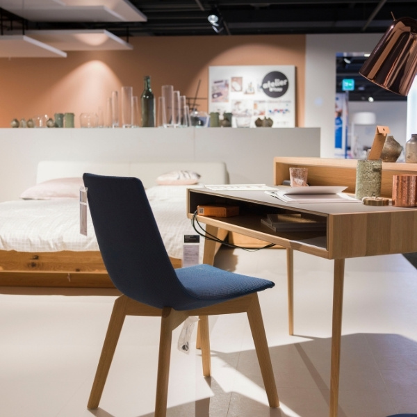A stylish showroom area at Pfister featuring a desk, chair, and bed – customer reference for the use of the BSI Customer Suite in retail