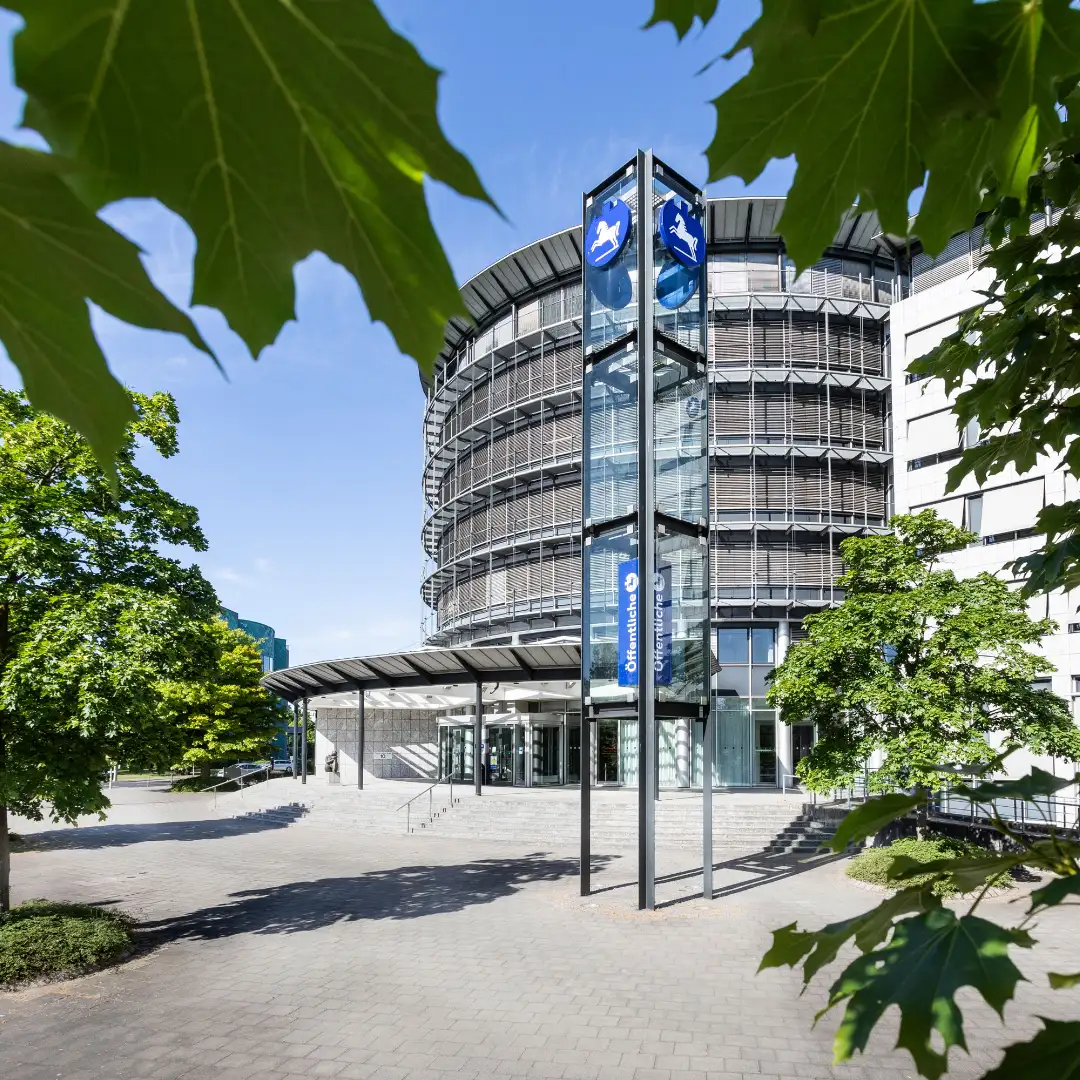 Modernes Verwaltungsgebäude der Öffentlichen Versicherung Braunschweig (ÖVBS), Kundin von BSI Software, mit markanter Glasfassade und begrüntem Vorplatz.