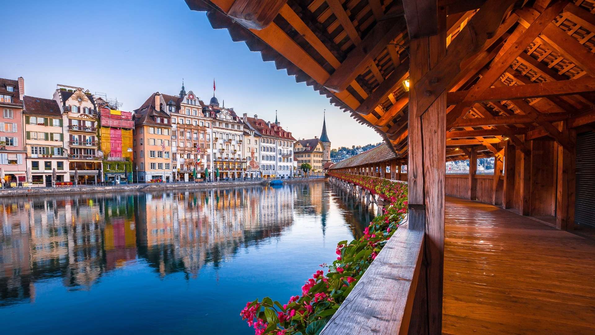 Blick von der historischen Kapellbrücke über die Reuss auf die farbigen Häuserfassaden der Luzerner Altstadt mit Spiegelungen im Wasser. Luzern ist der jüngste Standort von BSI Software in der Schweiz.
