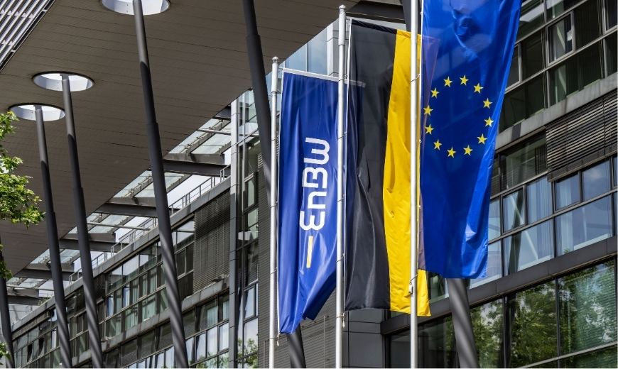 Exterior view of a modern office building with the flags of EnBW and the European Union waving – a visual statement of the new partnership between energy company EnBW and BSI in the field of Customer Relationship Management.